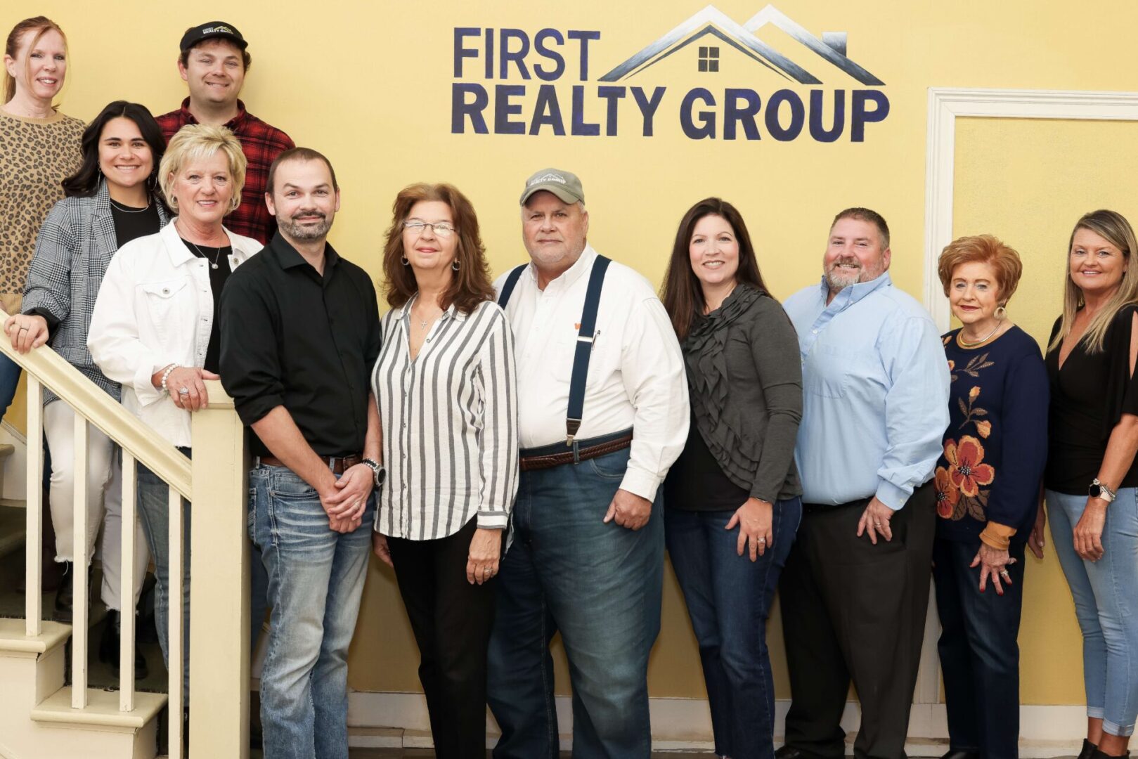 A group of people standing in front of the first realty group sign.